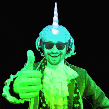 a man wearing a green unicorn hat and sunglasses gives a thumbs up