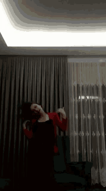 a woman in a red top is dancing in front of a couch