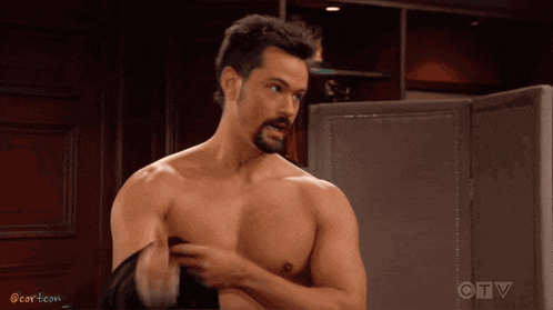 a shirtless man is standing in front of a safe with ctv written on the bottom right