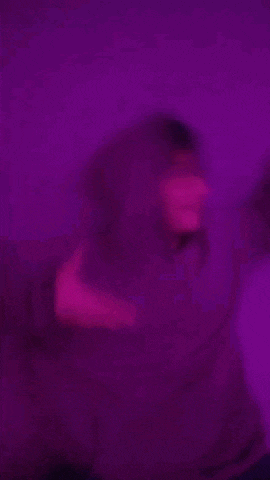 a blurry picture of a man in a purple shirt standing in front of a purple background .