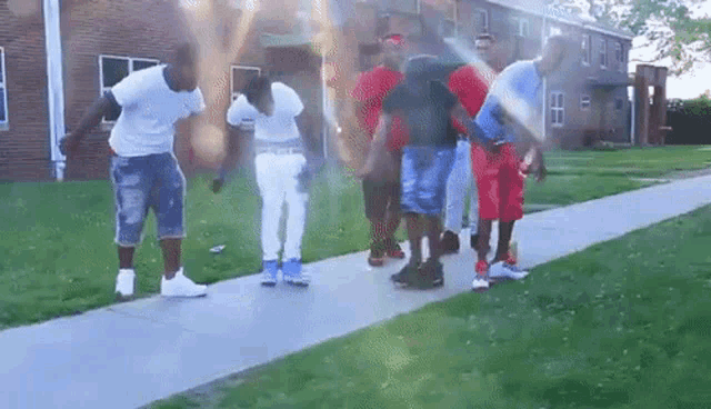 a group of young men are standing on the sidewalk in front of a brick building .