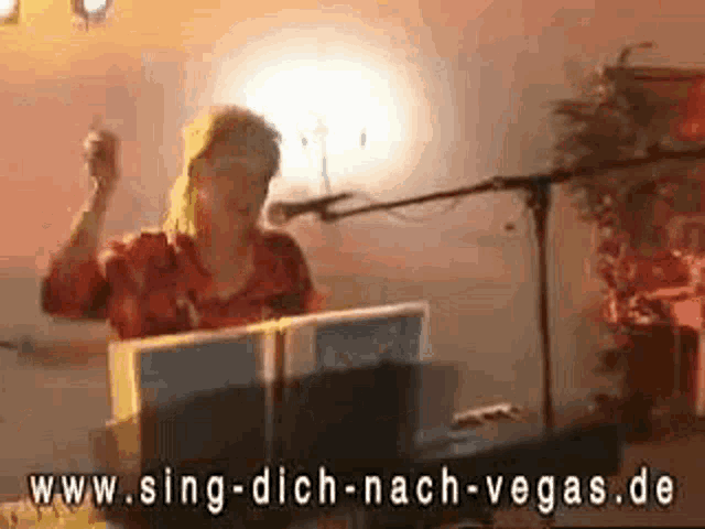 a woman is singing into a microphone while playing a keyboard