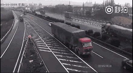 a red truck is driving down a highway next to a row of cars .