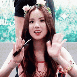a girl with a flower crown on her head is holding a pen in her hand .