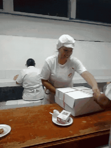a woman wearing a white hat and apron is packing a box