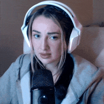 a woman wearing headphones and a hoodie is sitting in front of a microphone