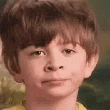 a close up of a young boy 's face with a yellow shirt on .