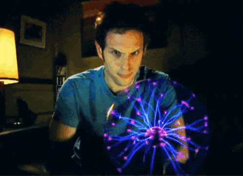 a man in a blue shirt holds a glowing ball in his hands