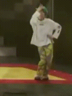 a person is standing on a trampoline wearing a white shirt and green pants