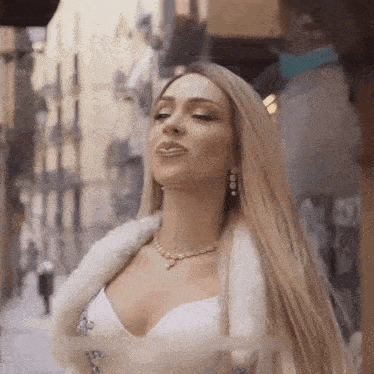a woman with long blonde hair and a fur coat is standing on a city street .