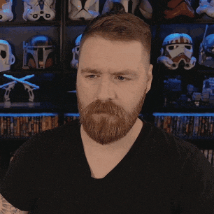 a man with a beard is standing in front of a shelf with storm trooper helmets on it