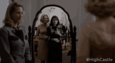two women are standing in front of a mirror and looking at themselves .