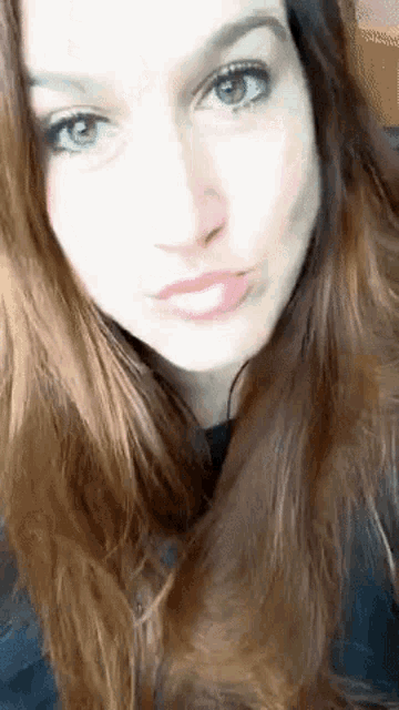 a close up of a woman 's face with long red hair and green eyes