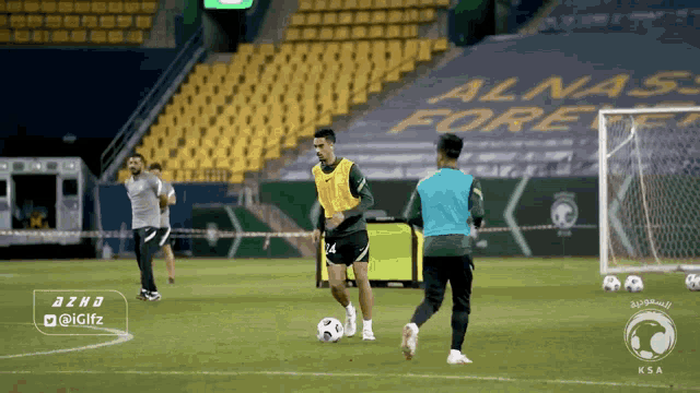 a soccer player kicks a ball in front of an empty stadium with the word alnas fore written on it