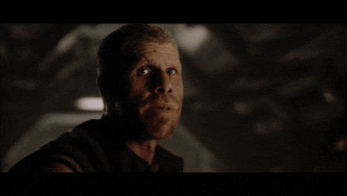 a man in a dark room with the words what a shithole above him