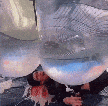 a man is laying in a bubble with a fan in it .