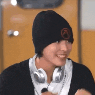 a young man wearing headphones and a beanie is smiling .