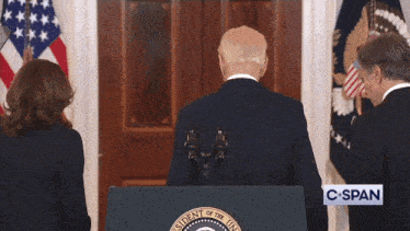 a man stands behind a podium with the president of the united states seal on it