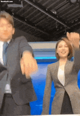 a man in a suit and tie and a woman in a suit are dancing together