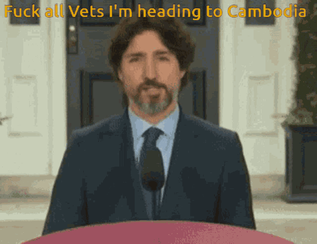 a man in a suit and tie stands in front of a microphone and says fuck all vets i 'm heading