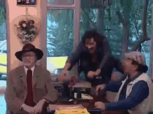 a group of men are sitting at a table and one of them is holding a knife