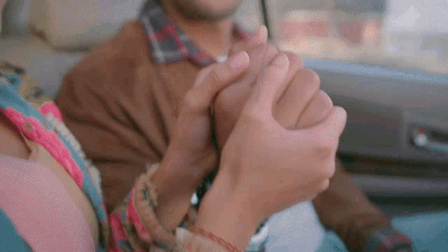 a man and woman hold hands in a car