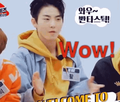 a young man wearing a yellow hoodie and a blue jacket is making a surprised face .