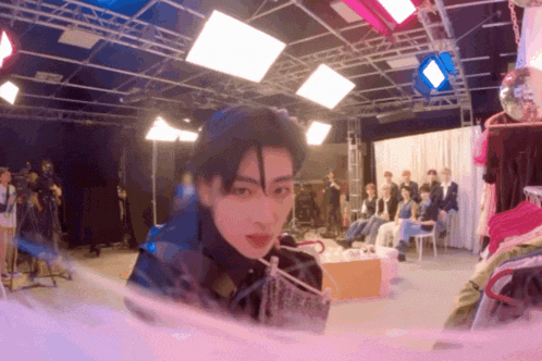a blurry photo of a man in a room with a group of people behind him