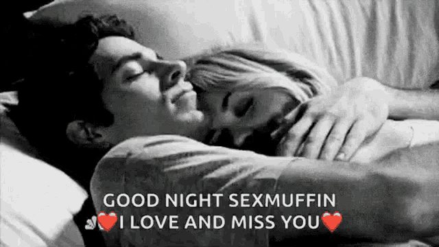 a man and a woman are laying in bed hugging each other . the man is kissing the woman on the forehead .
