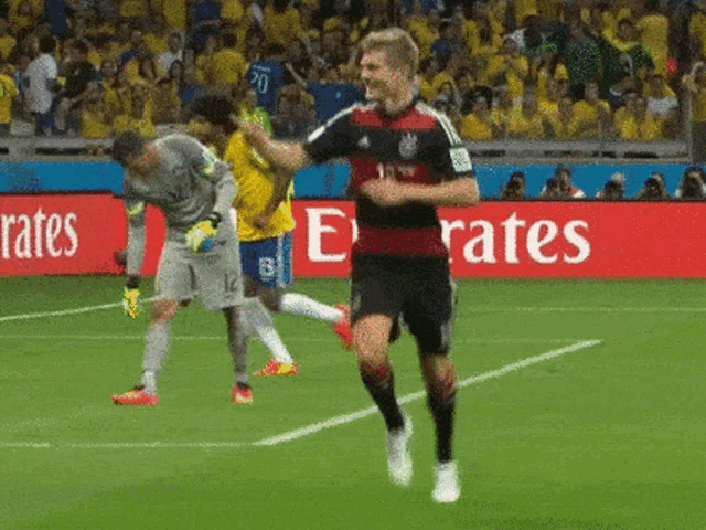 a soccer player is running on the field in front of a emirates sign