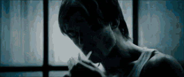 a man smoking a cigarette in front of a window