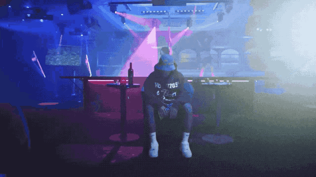 a man wearing a hoodie that says vc 7705 sits at a table