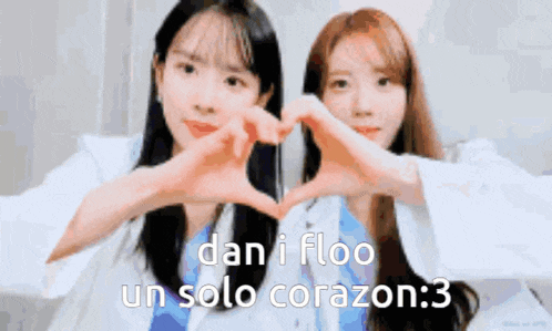 two women are making a heart shape with their hands