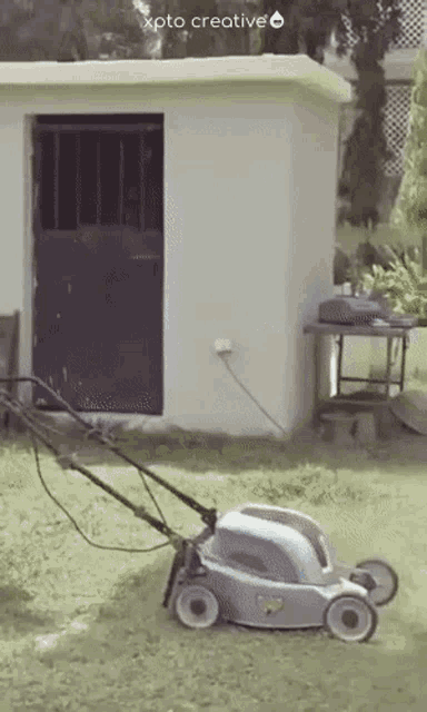 a lawn mower is sitting in front of a shed with xpto creative on the bottom