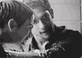 a black and white photo of two men looking at each other in a mirror .