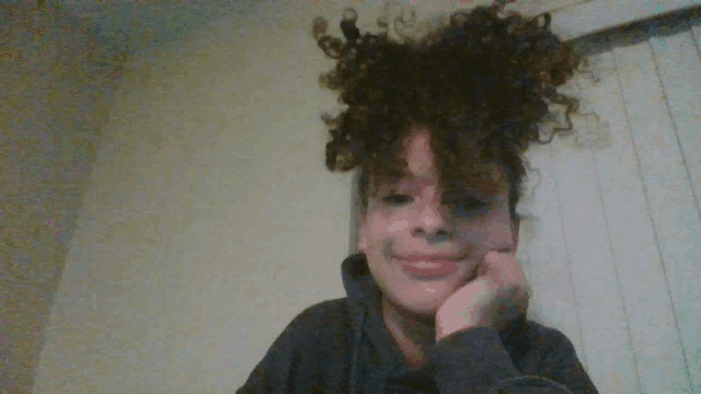 a girl with curly hair has her hand on her face