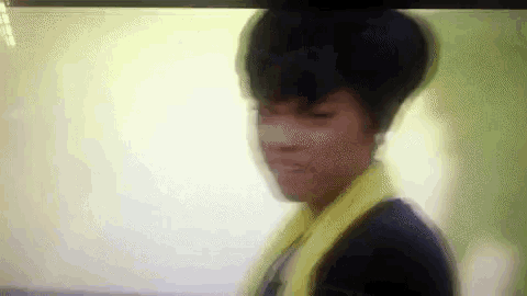 a blurry picture of a woman wearing a yellow scarf and a black shirt .