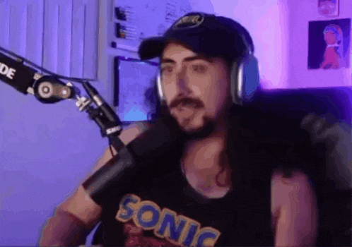 a man with long hair is wearing headphones and a sonic shirt .