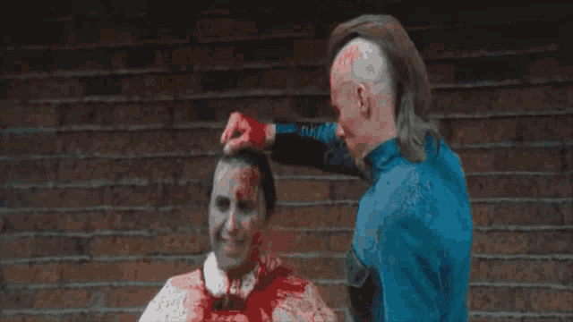 a man in a blue jacket is holding a bloody knife next to a bloody skeleton
