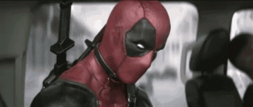 deadpool is sitting in the back seat of a car holding a gun and looking at the camera .