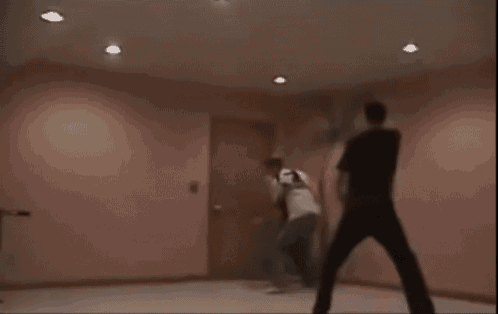 two men are fighting in a room with a door in the background