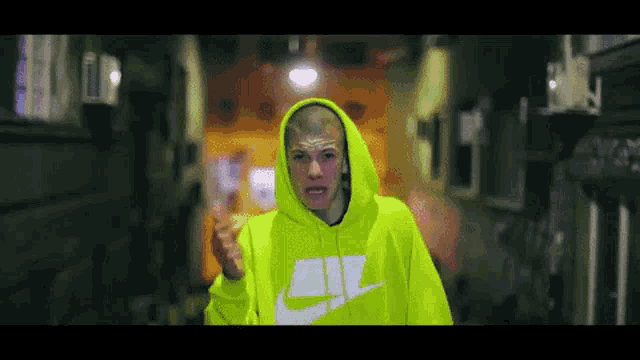 a man wearing a neon yellow nike hoodie is giving a middle finger