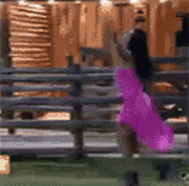 a woman in a pink dress is standing in front of a fence
