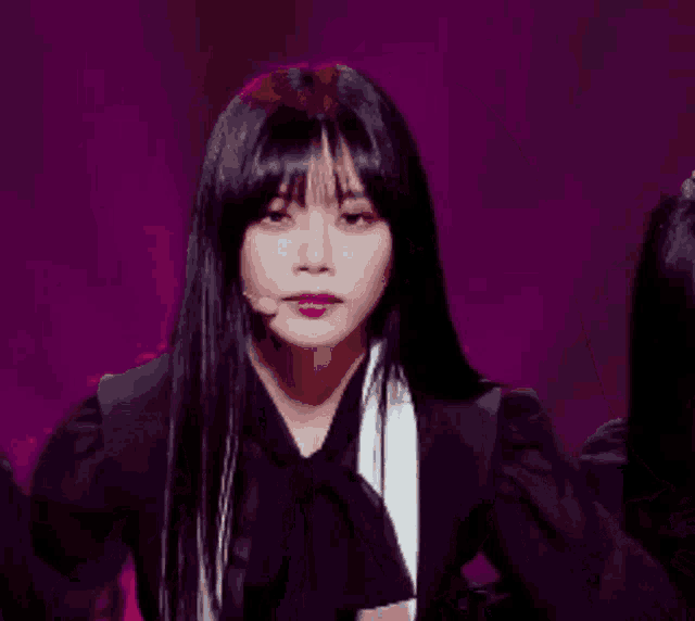 a woman with long black hair is wearing a black jacket and a white scarf
