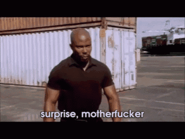 a man in a black shirt is standing in front of a white container and says surprise motherfucker .