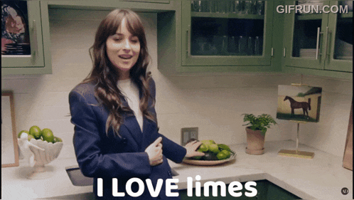 a woman standing in a kitchen with a bowl of limes and a sign that says i love limes
