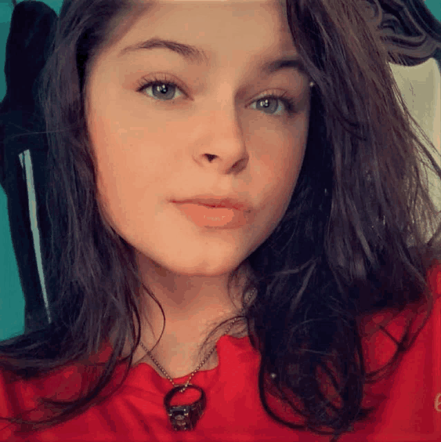 a woman wearing a red shirt and a necklace with a skull pendant