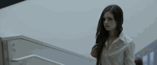 a woman in a white shirt is walking down a set of stairs with the number 3 on the wall behind her