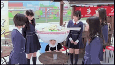 a group of girls are standing around a person wearing a ramen head