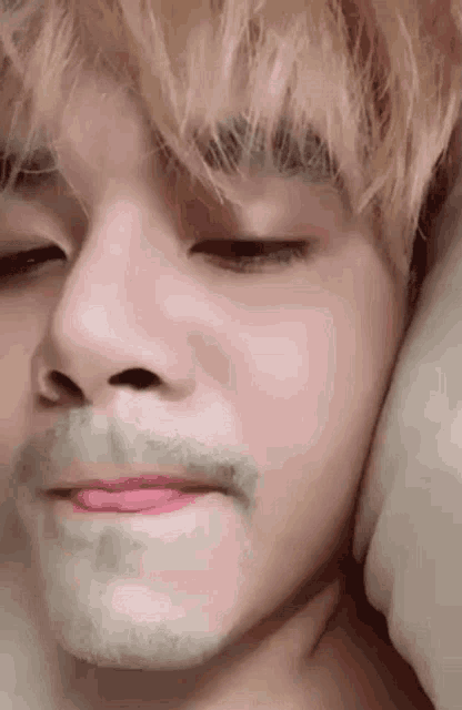 a close up of a person 's face with a beard and a pink lip .